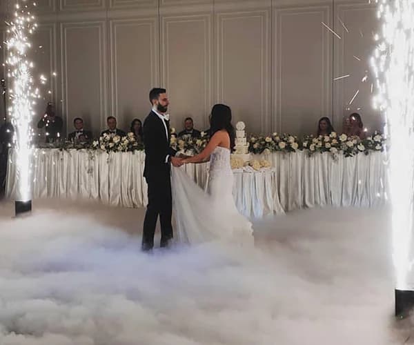 Primer baile de una pareja entre humo bajo y fontanas